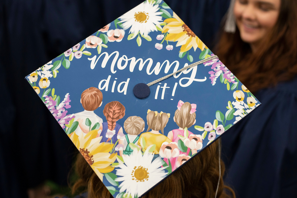 Graduate ceremony with graduate cap reading "Mommy did it!"