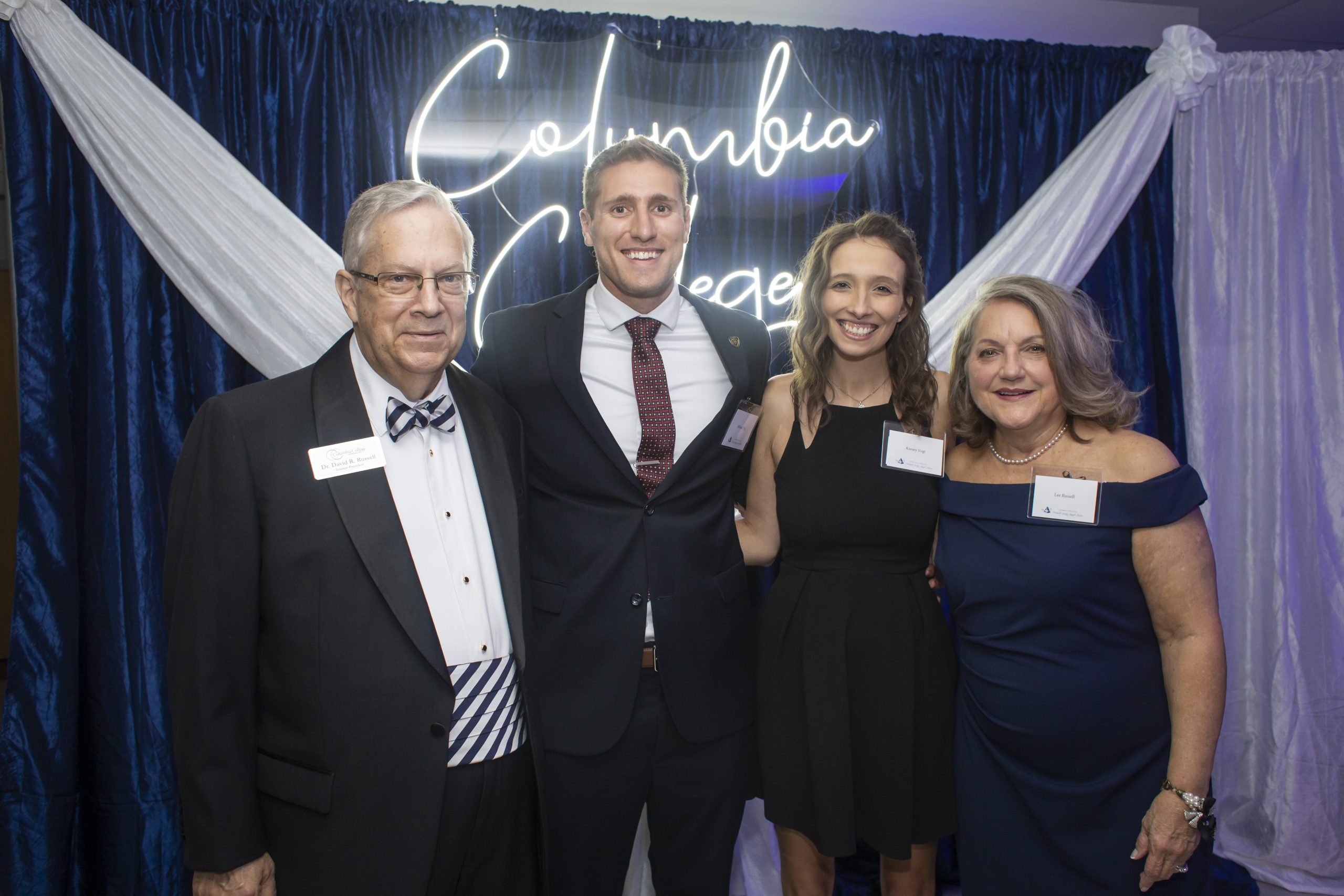 Michael Vogt posed with his wife, Kinsey, the President of Columbia College - Dr. Russell and his wife Lee Russell in front of a LED sign for Columbia College