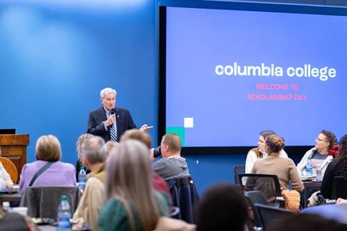 Speaker standing while welcoming students to Scholarship Day in New Hall.