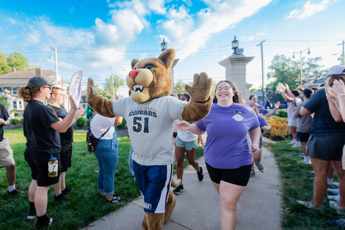 Scooter and incoming freshman running through Rogers Gate during the Storm the Gate celebration.