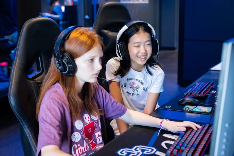 Two female Game Dev 2.0 campers enjoy their time in front of computer.