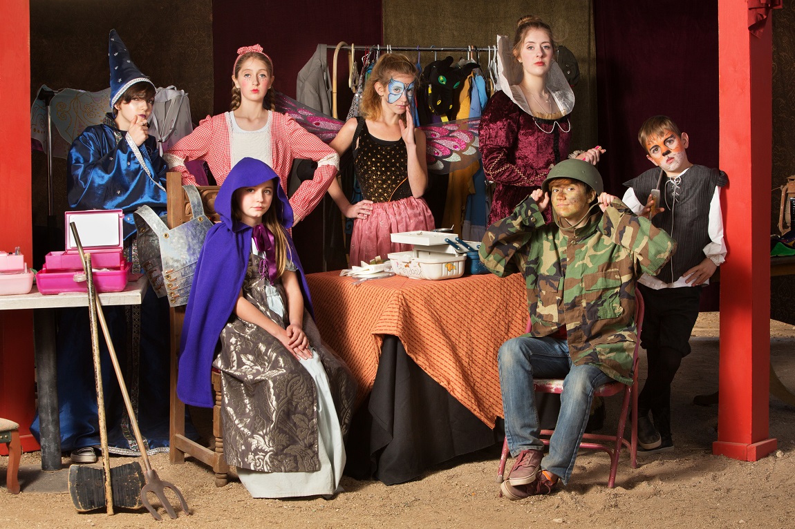 Seven campers seated or standing around a table in full theatre regalia.