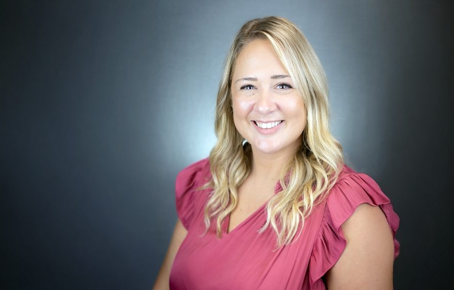 Headshot of Dr. Alaina Leverenz, wearing a short-sleeved pink shirt, smiling at the camera.