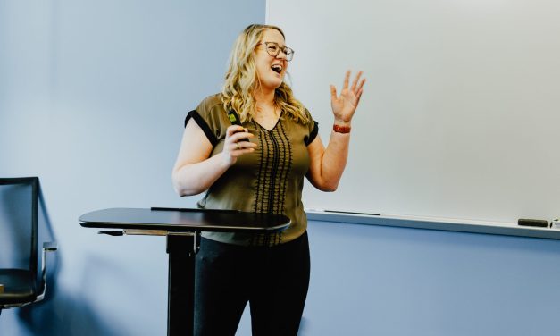 Dr. Alaina Leverenz standing at podium in classroom, teaching marketing students.