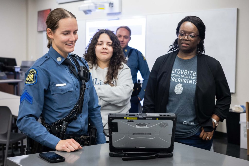 Two students, flanked by two members of the Missouri State Highway Patrol, participate in a demonstration during the patrol’s visit to a Columbia College Forensic Chemistry class.