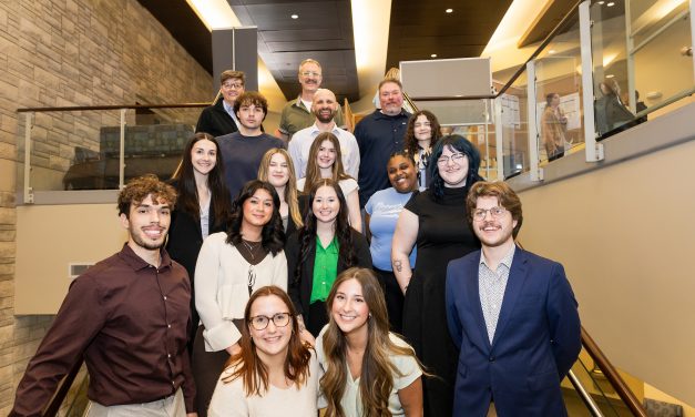 Group of students standing on the stairs in Atkins Holman Center during the School of Arts & Sciences week long showcase.