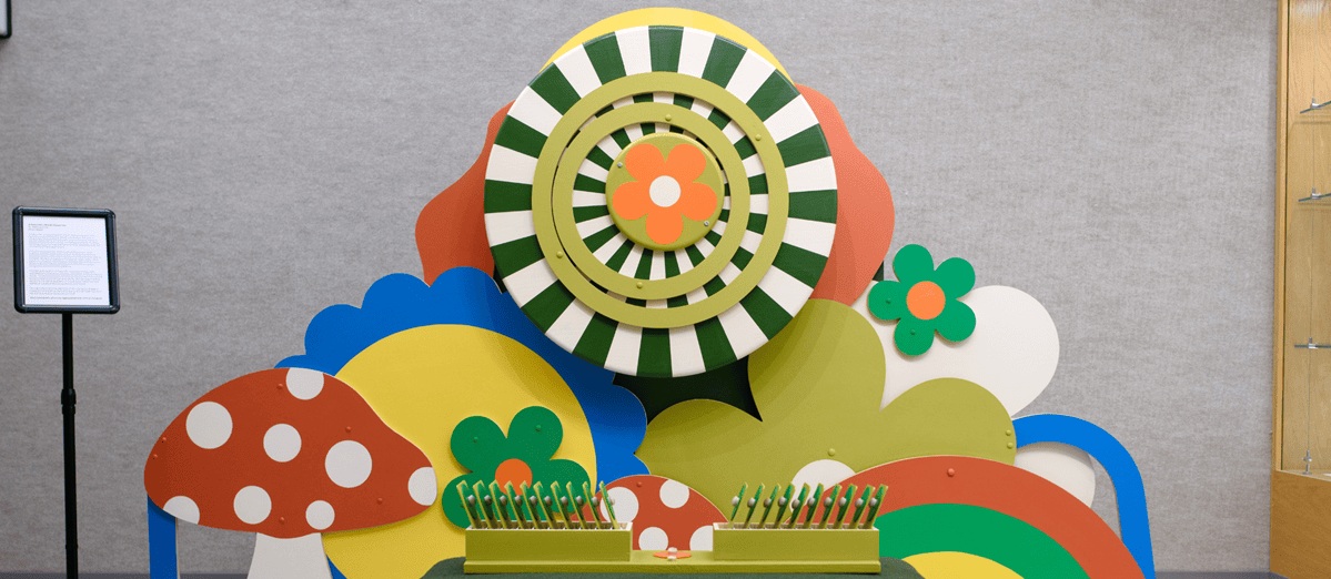 Colorful wall size composition by faculty member Bethanie Irons, with a red polka-dotted mushroom, a rainbow, and several flower petals.