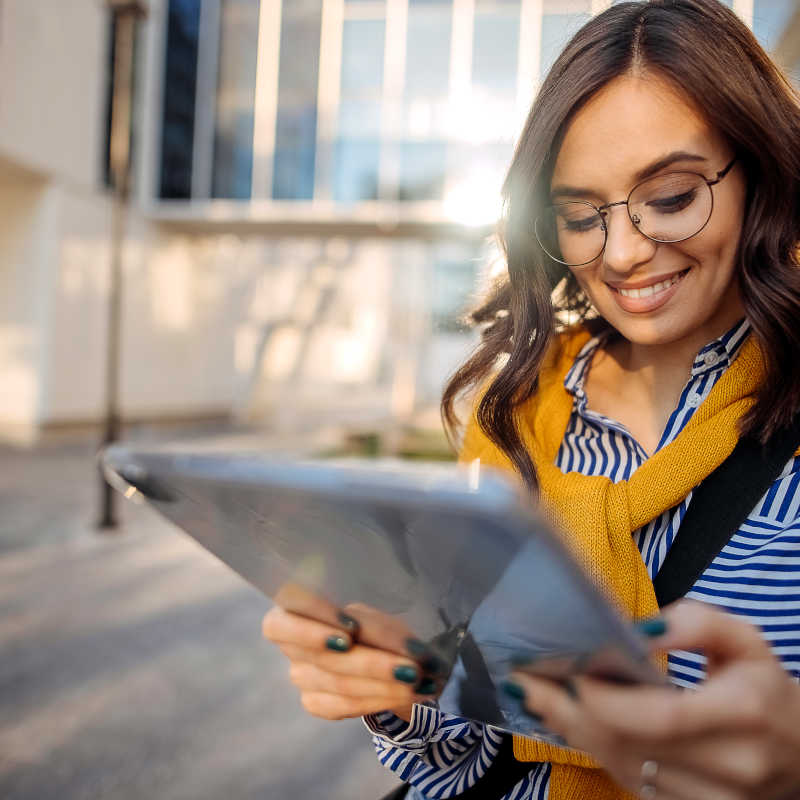 myPortal: Woman with long brown hair and wearing glasses working on a tablet.