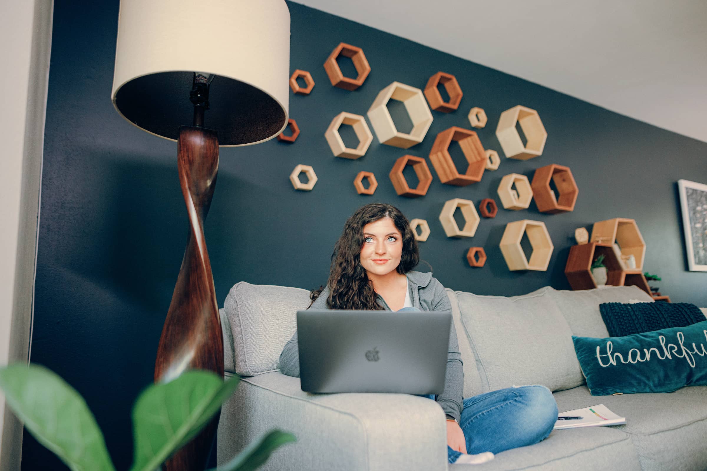Adult student, sitting on her couch with a laptop propped in front of her, studying for her Cybersecurity Master degree.