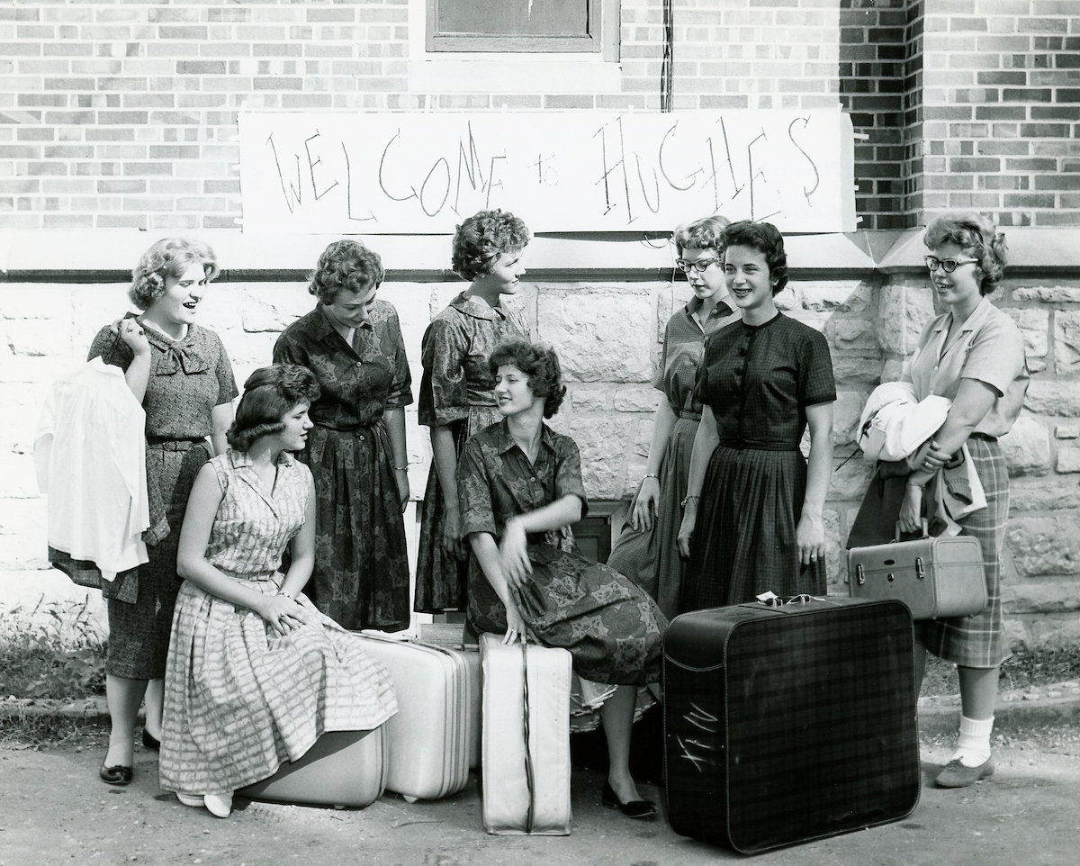 Historical image of a group of women standing or sitting by luggage.