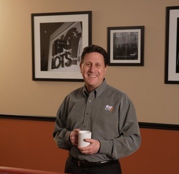 Portrait of Steve Fishman, a former CEO of Big Lots, Inc, and a former trustee of Columbia College, holding a coffee mug.